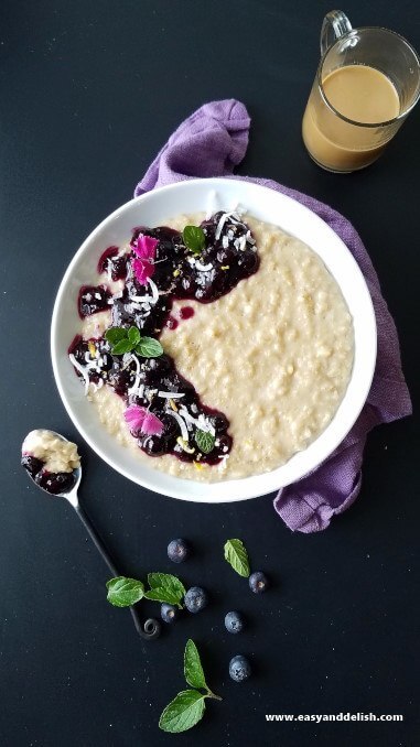 A bowl of coconut oatmeal pudding topped with blueberry sauce