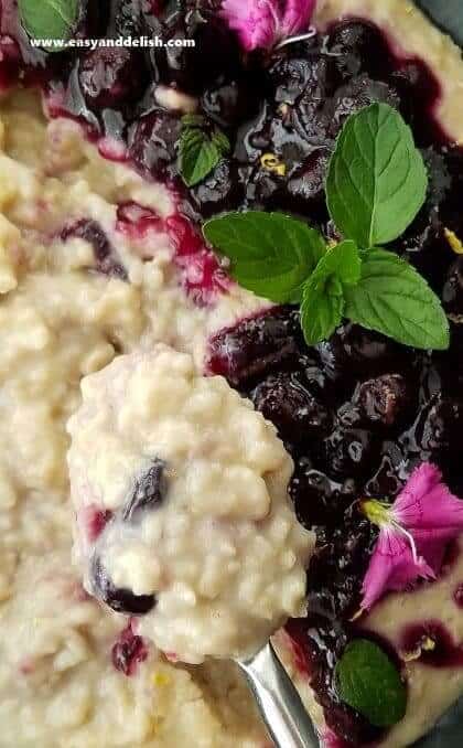 Overhead shot of a spoon full oatmeal above a bowl of oatmeal topped with blueberry sauce.