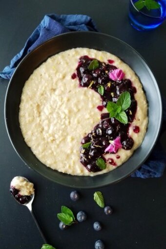 a bowl of oatmeal with blueberries and flowers