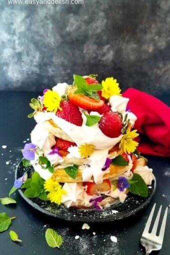 a pile of strawberry pancakes garnished with berries and flowers