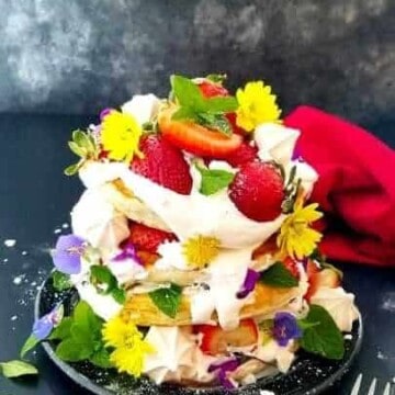 a pile of strawberry pancakes garnished with berries and flowers
