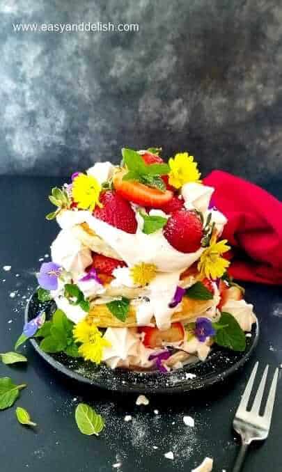 a pile of strawberry pancakes garnished with berries and flowers