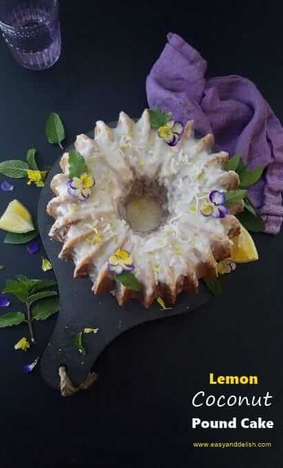 Overhead view of lemon coconut pound cake with garnishes on the side and a cup of water at the background.