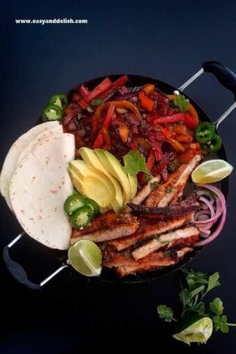 close up of pork fajitas with tortillas on the side