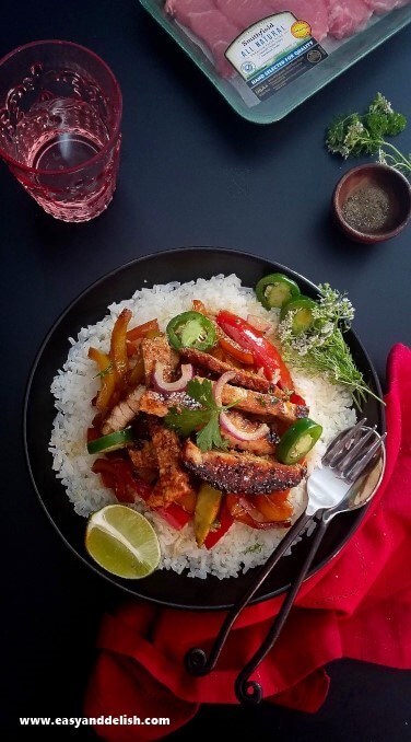 Pork fajita bowl served with rice and a glass of water on the side