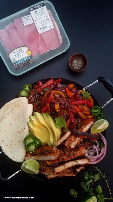 Pork fajita bowl served in a skillet with tortillas on the side.