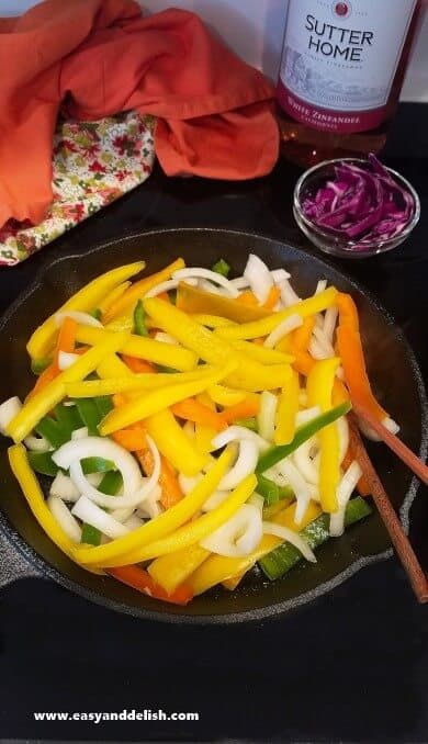 Vegetables for spicy taco shrimp fajitas being cooked in a skillet on stovetop