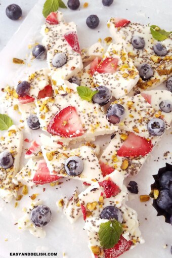 many pieces of the Frozen yogurt bark on parchment paper.