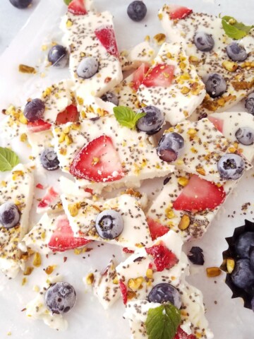 many pieces of the Frozen yogurt bark on parchment paper.