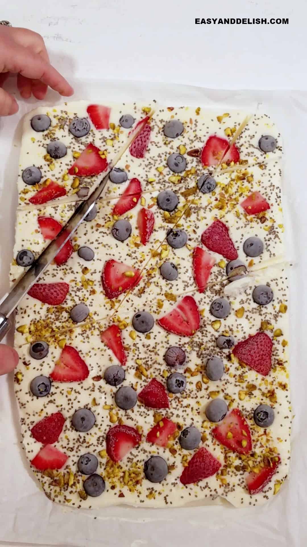 a knife cutting frozen yogurt bark into pieces. 