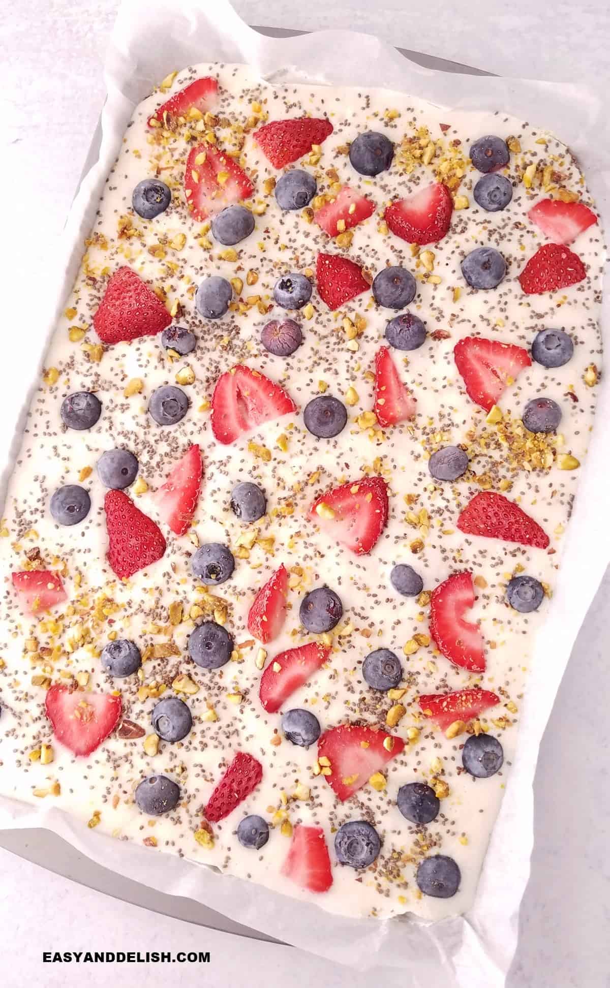 whole frozen yogurt bark with berries in a baking sheet. 