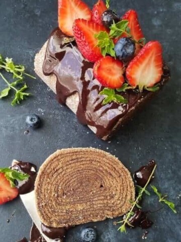 chocolate cake roll topped with berries and partially sliced