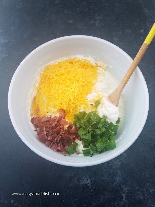 Bowl with ingredients for loaded mashed potato skillet being mixed