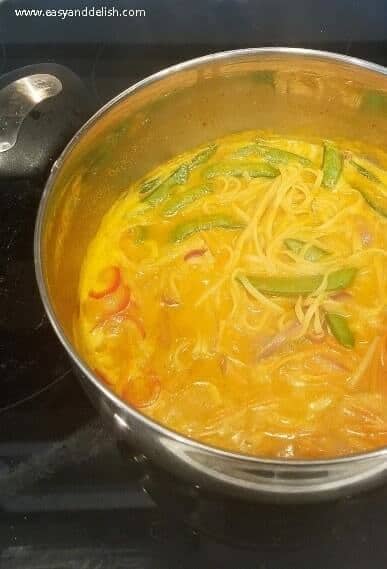 one pot coconut noodle soup being prepared in a large pot on stovetop