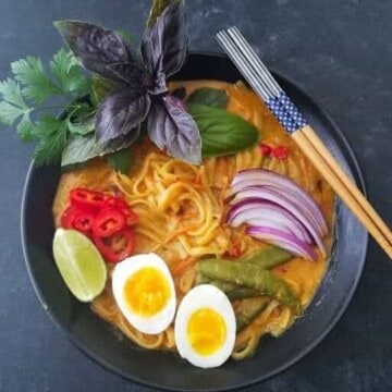 A bowl of coconut noodle soup with chopsticks on the side