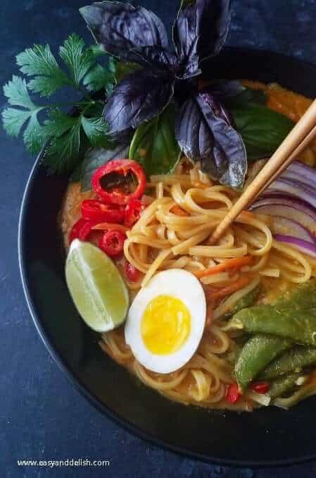 one pot coconut noodle soup being mixed with chopsticks