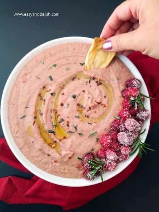 A bowl of cranberry jalapeno dip with pita chips. 