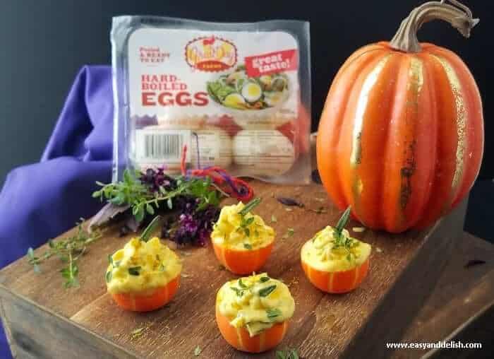 Curried pumpkin deviled eggs on a tray with product on the background