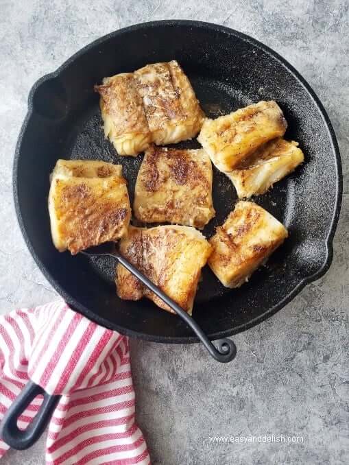 pan-fried cod fillets in a cast-iron pan