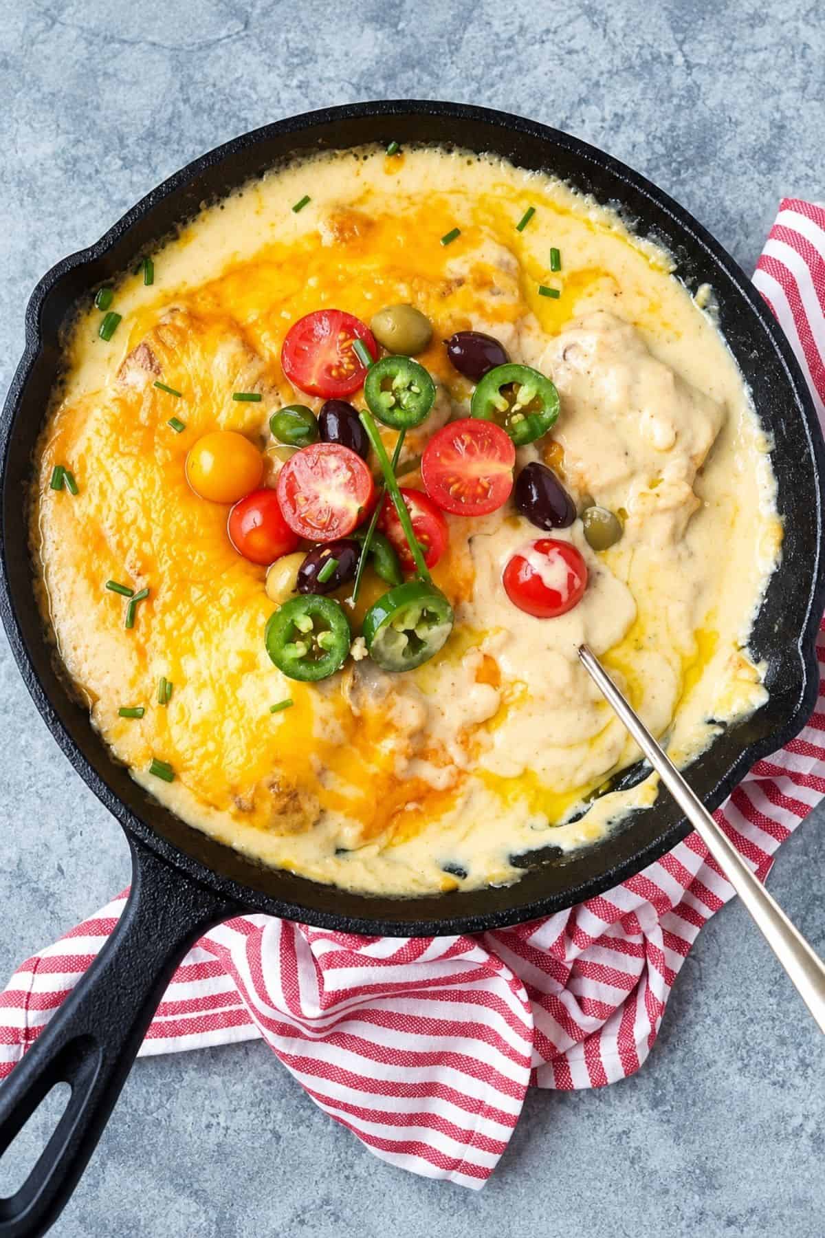Baked cod with cheese sauce topped with fresh tomato, olives, jalapeño, and chives.