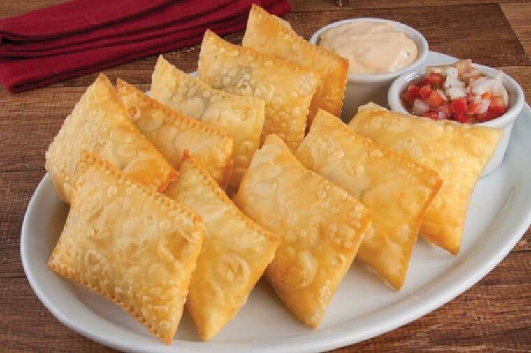 cheese fried empanadas served in a platter with salsa