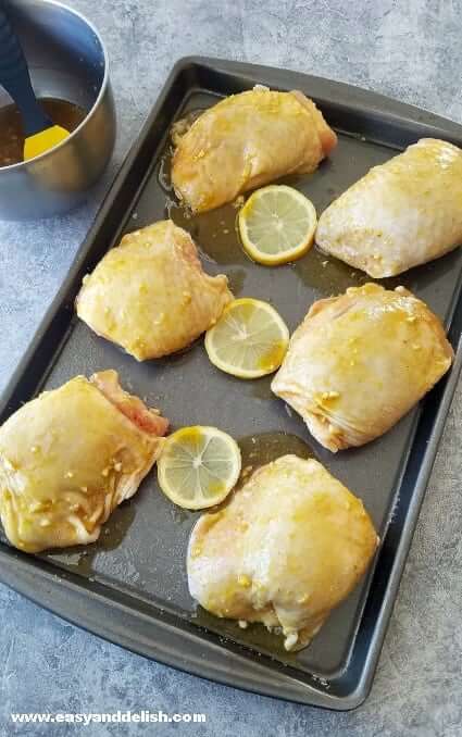 Thighs in a baking sheet with lemon slices.