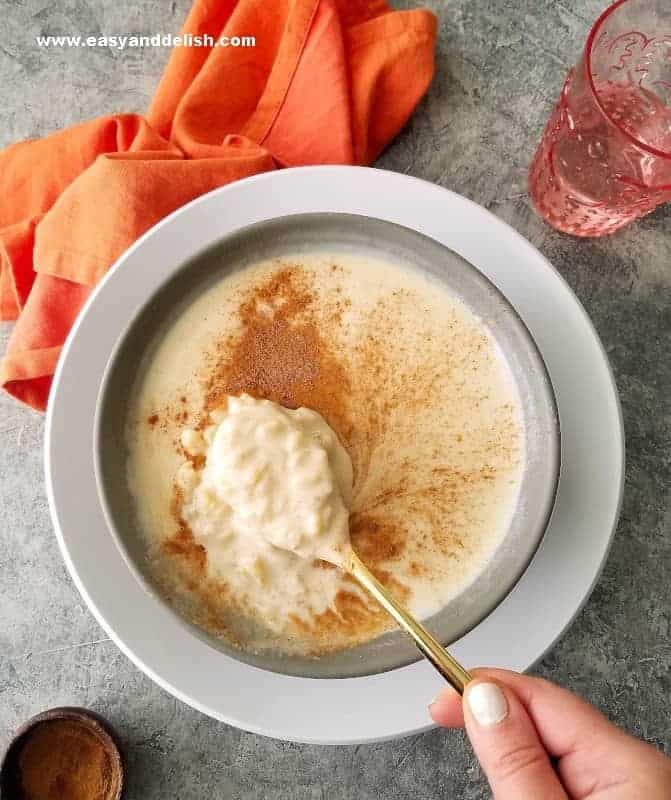 slow cooker rice pudding served in a bowl and being eaten with a spoon