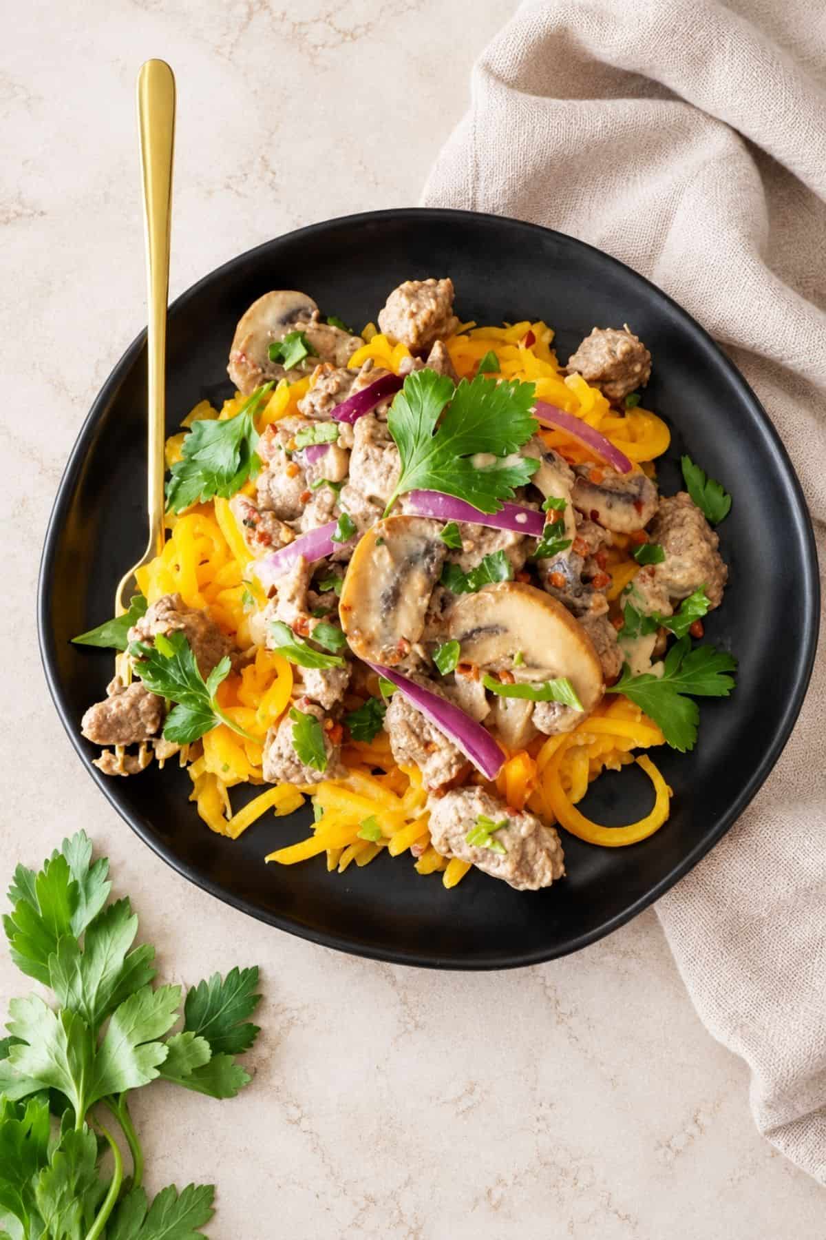 Beef stroganoff served over spaghetti squash with mushrooms, red onion, bell pepper, and fresh parsley.