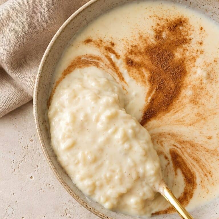 Creamy slow cooker rice pudding on a gold spoon with cinnamon.