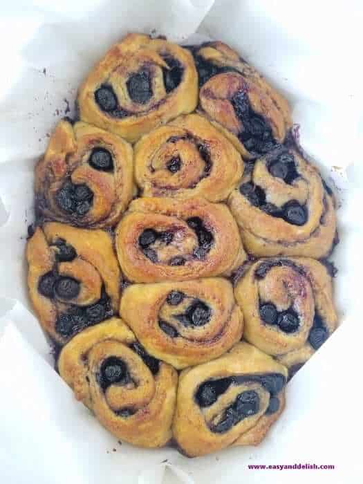 baked blueberry pie cinnamon rolls in a baking pan before being frosted 