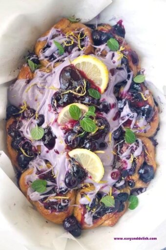 cinnamon rolls topped with blueberry icing and lemon slices