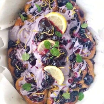 cinnamon rolls topped with blueberry icing and lemon slices