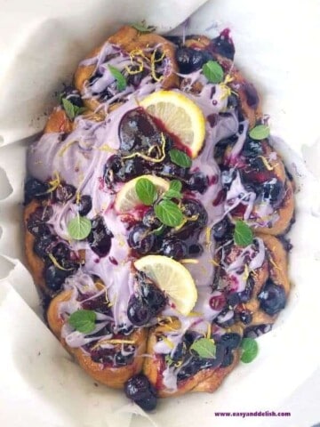 cinnamon rolls topped with blueberry icing and lemon slices