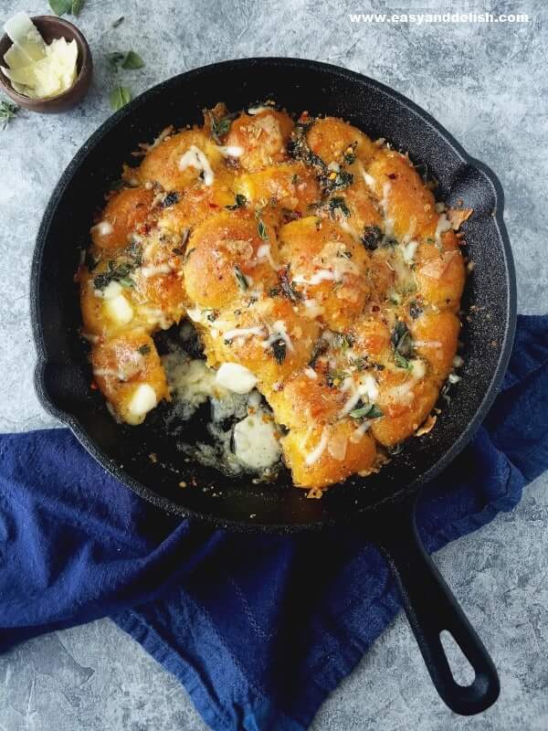 garlic bread rolls in a skillet with cheese on the side