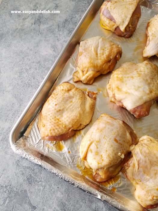 marinaded and uncooked chicken thighs in a sheet pan