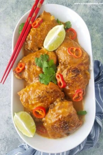 A platter of chicken satay with lemon wedges and chopsticks on the side