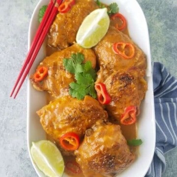 A platter of chicken satay with lemon wedges and chopsticks on the side