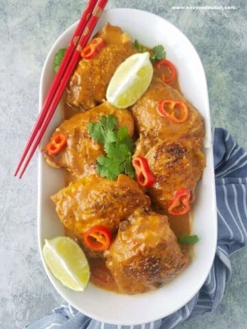 A platter of chicken satay with lemon wedges and chopsticks on the side