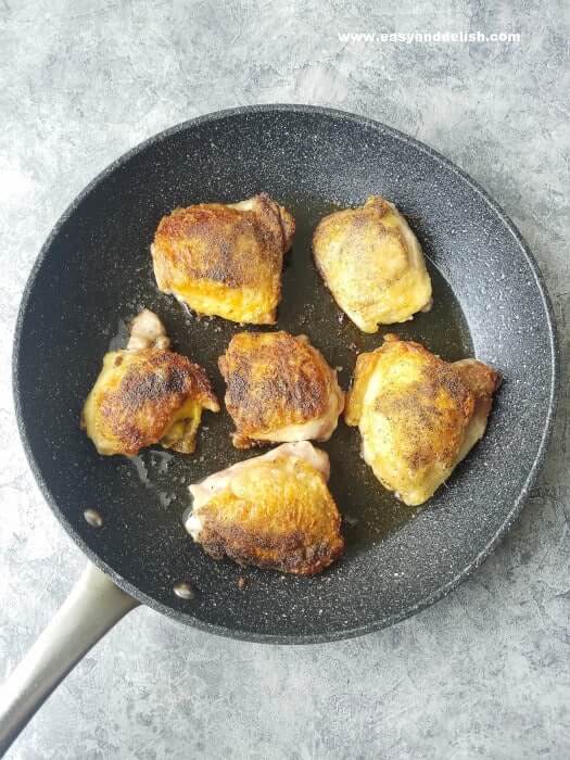 chicken thighs being browned in a skillet