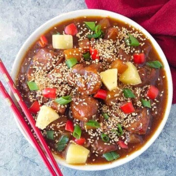 A bowl of sweet and sour pork made in the pressure cooker and chopsticks on the side