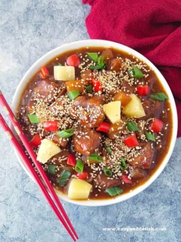 A bowl of sweet and sour pork made in the pressure cooker and chopsticks on the side