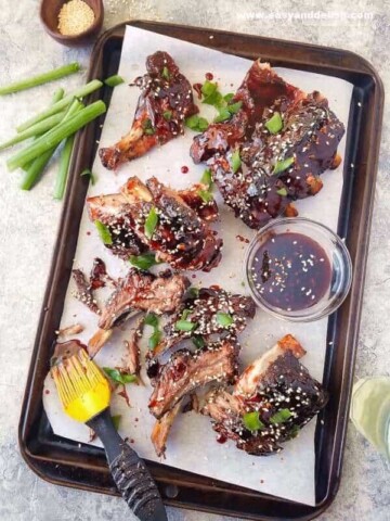 Chinese barbecue ribs in a baking sheet with green onions of the side and top