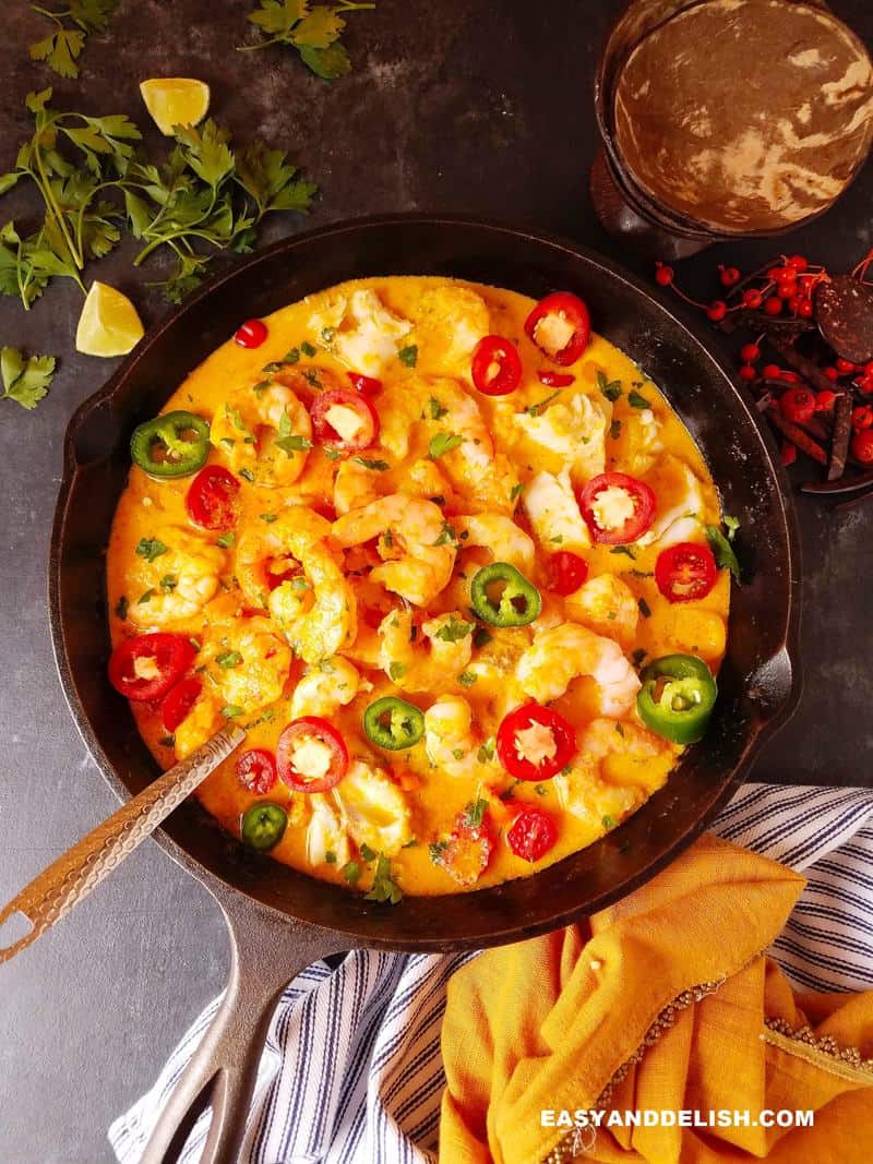 Brazilian moqueca in a pan with garnishes around