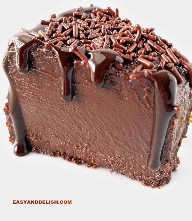 A close up of a slice of brigadeirao with chocolate sauce pouring from top to bottom