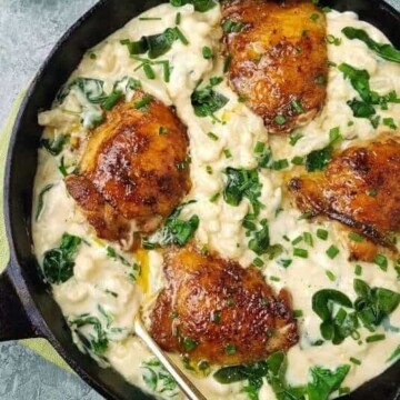 close up of a skillet of cauliflower mac and cheese with chicken thighs