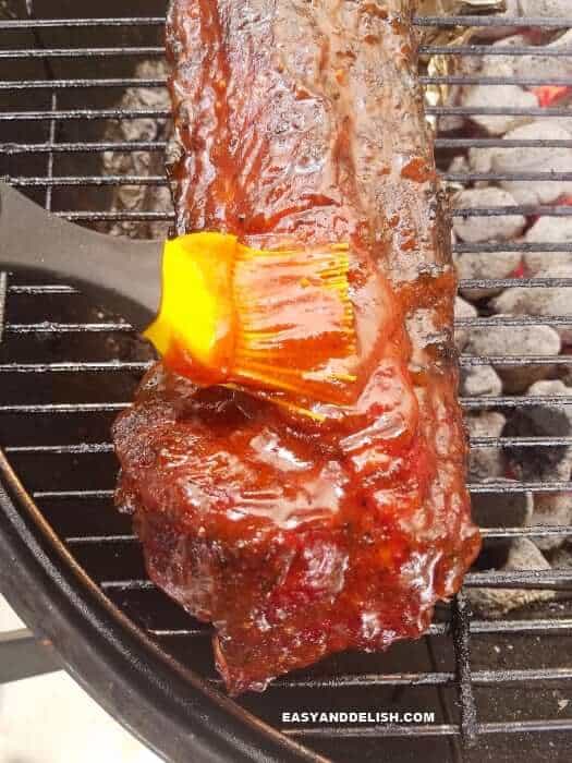 barbecue pork ribs being basted with sauce