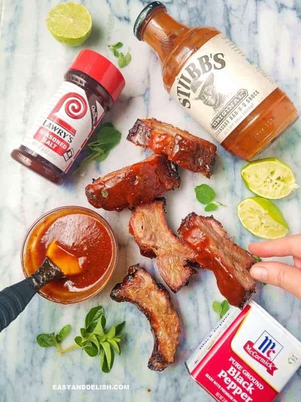 serving chipotle bbq pork ribson a board with sauce, herbs and lime