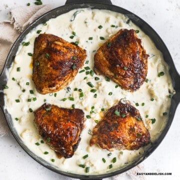 close up of a skillet with keto cauliflower mac and cheese, chicken thighs, and spinach