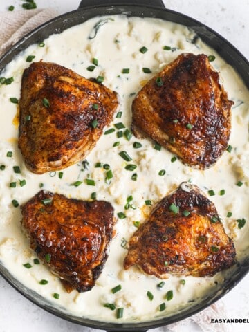 close up of a skillet with keto cauliflower mac and cheese, chicken thighs, and spinach