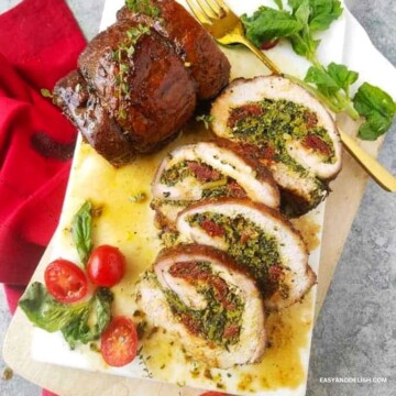 Partially sliced stuffed pork loin on a cutting board.